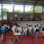 Na quadra coberta do CRPI, uma grande roda com cerca de 80 pessoas sentadas em cadeiras e bancos.