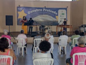 Pessoas assistem apresentação de grupo musical.